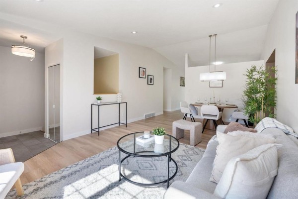 Open concept living and dining area with light wood floors, modern furniture, and a vaulted ceiling. - 11 Dufort Place, Winnipeg