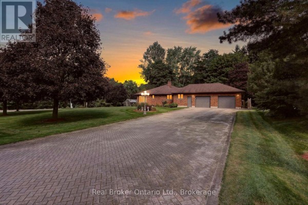 A ranch house with a double garage viewed from a long, paved driveway at sunset. - 11 Elisabeth Street, East Zorra Tavistock