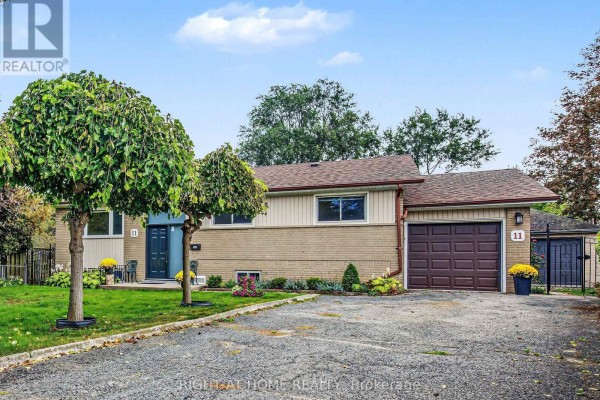 Exterior view of the house showcasing the brick facade, siding, and garage door. - 11 Fareham Crescent, Toronto