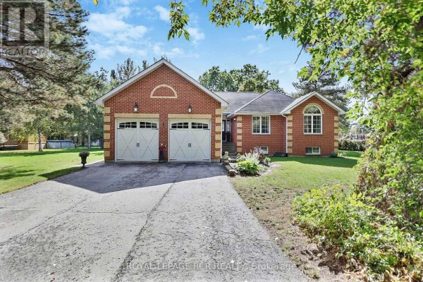 Front exterior of a single-story red brick house with a two-car garage and manicured lawn. - 11 Fisher Drive, Adjala Tosorontio