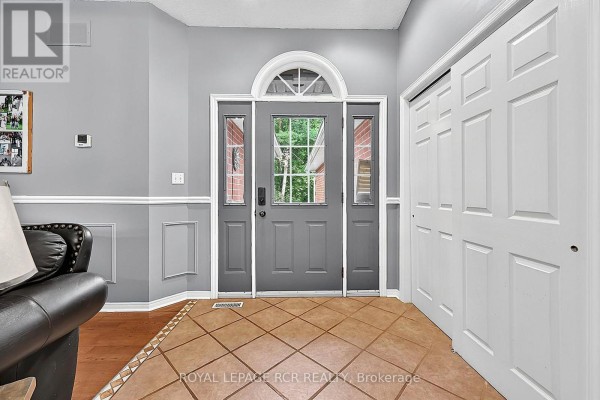 Foyer with beige tile floor, grey walls, a front door with sidelights, and a white bi-fold closet. - 11 Fisher Drive, Adjala Tosorontio