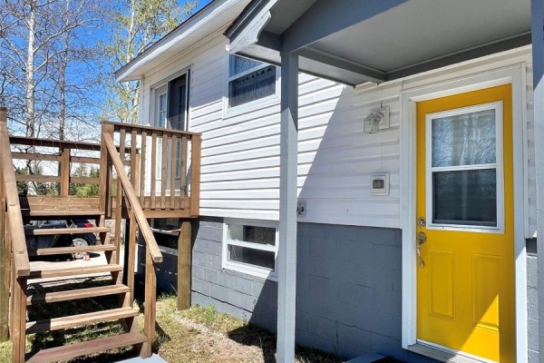 Close-up of the yellow front door with a wooden staircase and white vinyl siding on the bungalow. - 11 Fourth Avenue, Badger