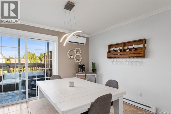 Dining area with a white table, grey chairs, and a sliding glass door leading to a balcony. - 11 Gagnon Drive, Moncton