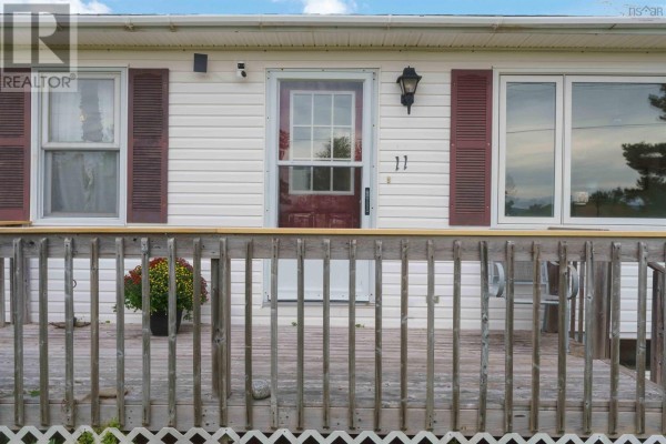 Close-up of the front entrance with a red door, windows, and a wooden deck. - 11 Green Lane, Falmouth
