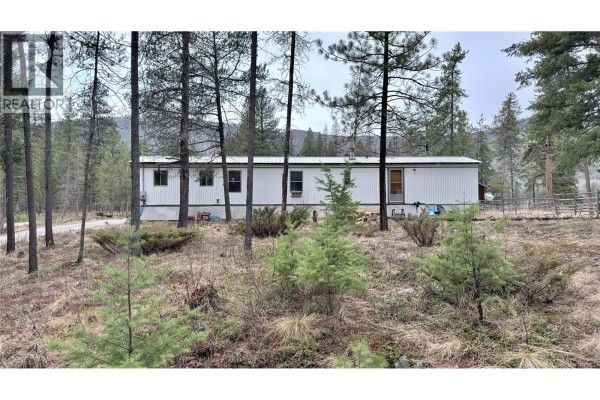 White property marker in a dry grassy field with forested hills beyond. - 11 Haggen Road, Beaverdell
