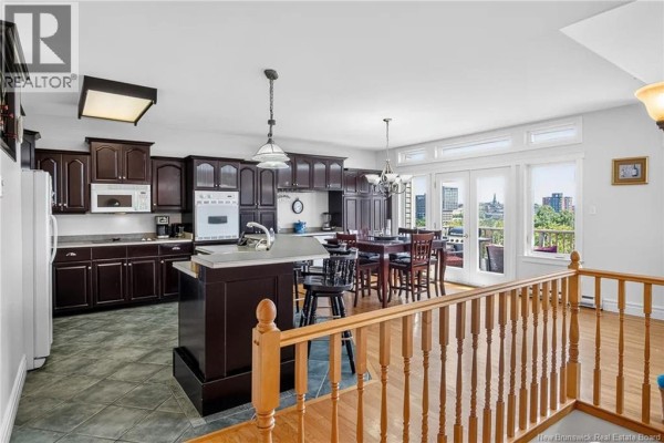 Open-concept kitchen and dining area with dark wood cabinets, a large island, and patio doors. - 11 Harbour Terrace, Saint John