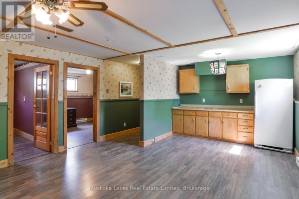 Kitchenette with wood cabinets, green walls, and doorways to other rooms. - 11 Harris Street, Muskoka Lakes