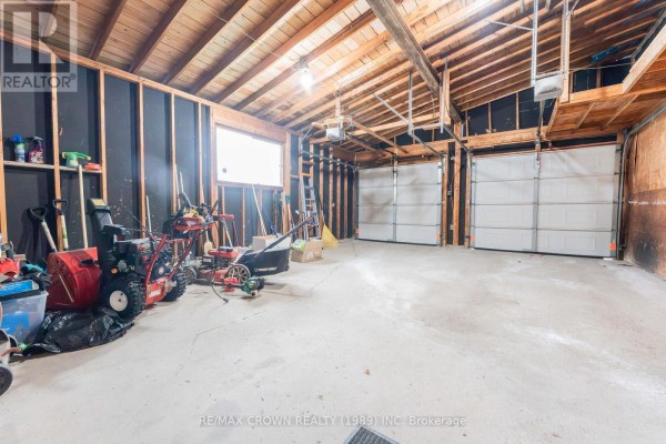 Interior of a spacious garage with exposed wooden beams and multiple garage doors. - 11 Kent Place, Kapuskasing