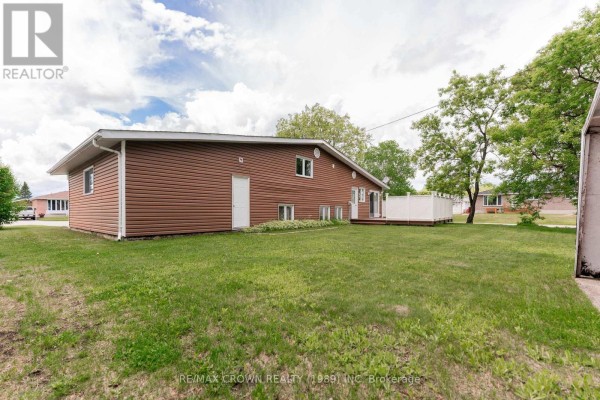Rear view of the house with a deck and grassy backyard. - 11 Kent Place, Kapuskasing