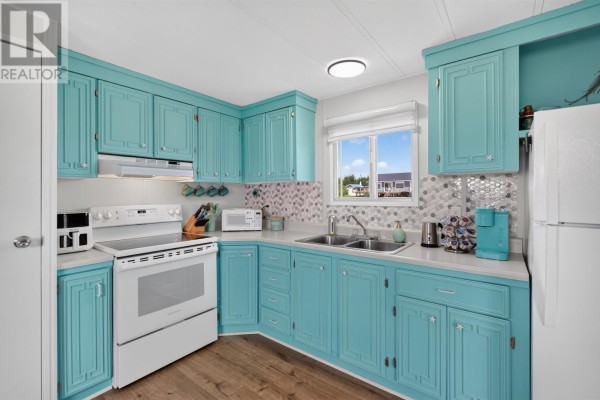 Kitchen with turquoise cabinets, white stove, microwave, air fryer, and hanging mugs. - 11 Macfadyen, Augustine Cove