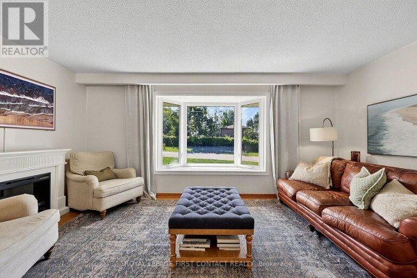 Living room featuring a fireplace, bay window, leather sofa, and upholstered chairs. - 11 Maclaren Avenue, Barrie