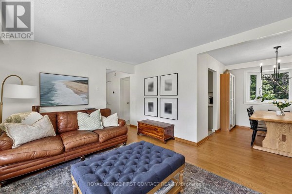 Living room and dining area with hardwood floors, artwork, and a large bay window. - 11 Maclaren Avenue, Barrie