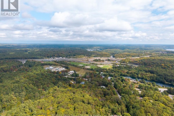 Aerial view of a highway interchange and surrounding forest with some scattered buildings. - 11 Oakridge Road N, Mcdougall