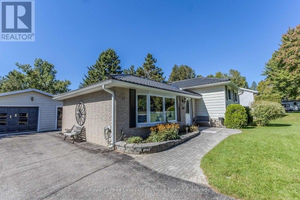 Side exterior view of the house, showing brick facade, paved walkway, and detached garage. - 11 Pine Street, Bracebridge