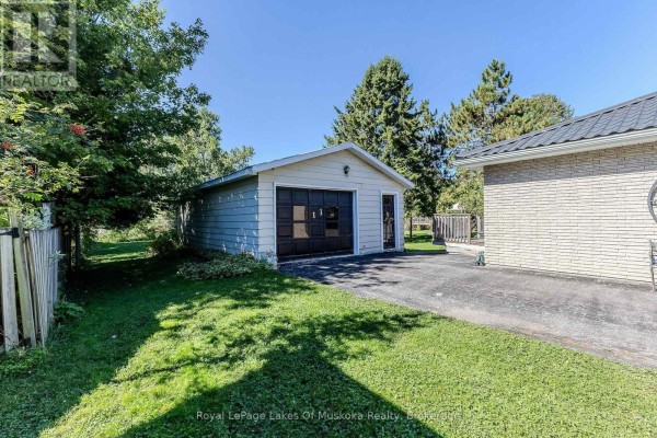 Detached single-car garage with gray siding and a black garage door, surrounded by grass. - 11 Pine Street, Bracebridge