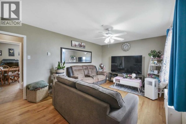 Living room with sofa, loveseat, television, and view into dining area. - 11 Poplar Crescent, Springbrook