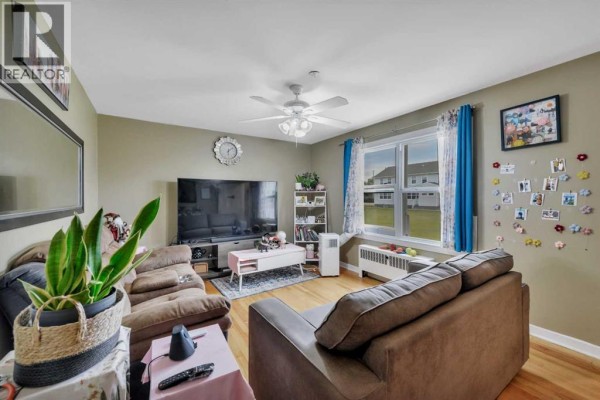 Living room with sofas, television, window view, and decorated wall. - 11 Poplar Crescent, Springbrook