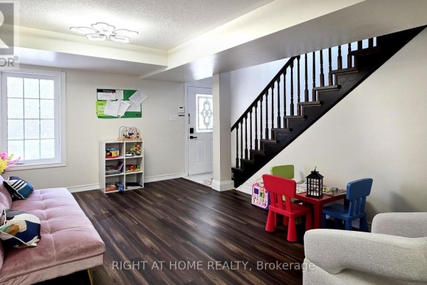 Finished basement with dark wood floors, pink sofa, and a kids' play area. - 11 Pottle Lane, Ajax