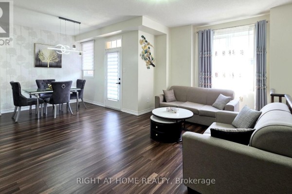 Living and dining area with dark wood floors and neutral-toned furniture. - 11 Pottle Lane, Ajax