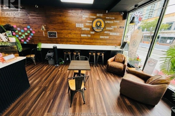 Seating area with tables, chairs, and lounge chairs inside a commercial space. - 11 Queen Street W, Brampton