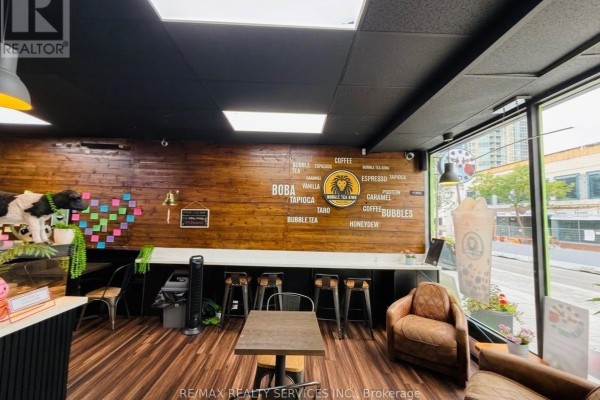 Commercial interior with wood-paneled walls, seating, and a large window view. - 11 Queen Street W, Brampton