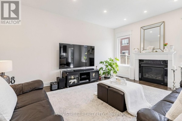 Living room with dark brown leather sofas, a large TV on a black media console, and a white marble fireplace. - 11 Robert Baldwin Boulevard, East Gwillimbury