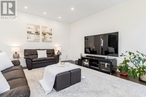 Living room showing seating arrangement with dark sofas, a coffee table, large TV, and decorative wall art. - 11 Robert Baldwin Boulevard, East Gwillimbury