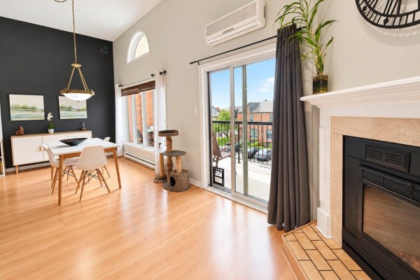 Dining area with a table, chairs, fireplace, and sliding glass door overlooking a street. - 11 Rue De Toulouse, #e, Gatineau
