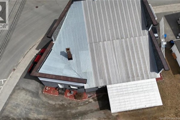 Overhead view of the building's pitched metal roof and surrounding asphalt. - 11 Rue St-jean Baptiste, Kedgwick
