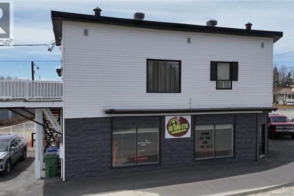 Front view of the commercial building with large windows and a sign reading "BIG JOHN GYM". - 11 Rue St-jean Baptiste, Kedgwick