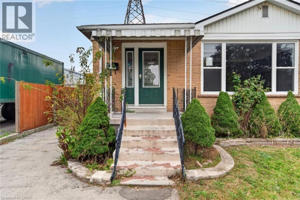 Close-up of the covered porch entrance with green double doors and ornate railings. - 11 Selkirk Avenue, Hamilton