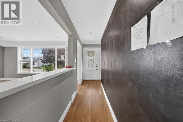 Interior hallway with wood flooring, grey accent wall, and view into living area. - 11 Selkirk Avenue, Hamilton