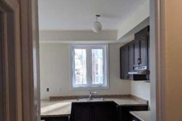 Kitchen with dark wood cabinets, granite countertops, and a window over the sink. - 11 Sprucewood Road, Brampton