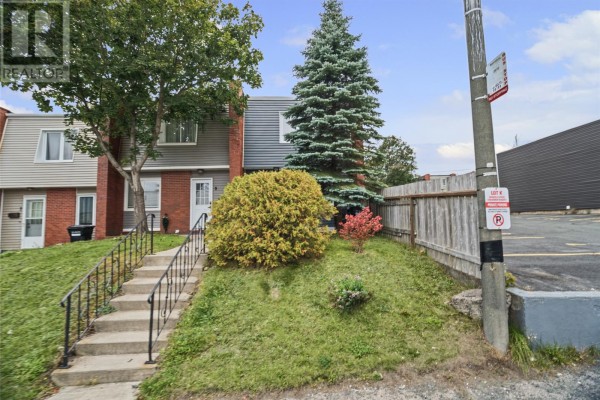 Street view of a row of townhouses on a grassy slope with a parking lot. - 11 Steer Street, St  John S