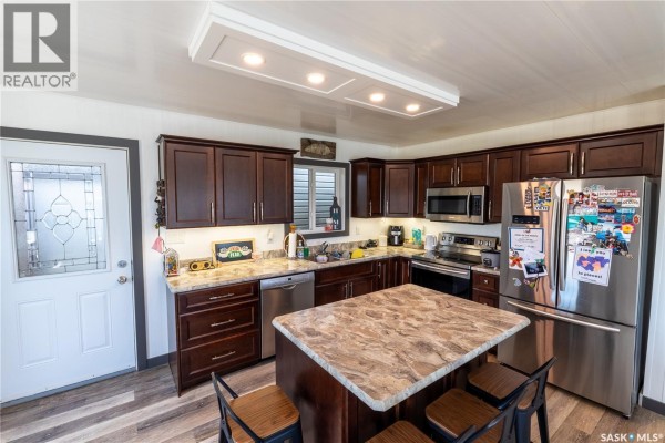 Kitchen with dark wood cabinets, granite countertops, stainless steel appliances, and an island. - 11 Sunrise Boulevard, Arm Lake