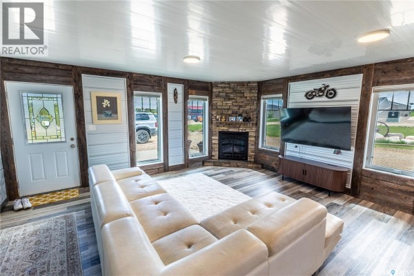 Living room with a large sectional sofa, fireplace, television, and large windows. - 11 Sunrise Boulevard, Arm Lake