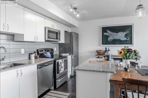 Kitchen view showing white cabinetry, granite island, stainless steel appliances, and a painting above the counter. - 11 Superior Ave Avenue, Toronto