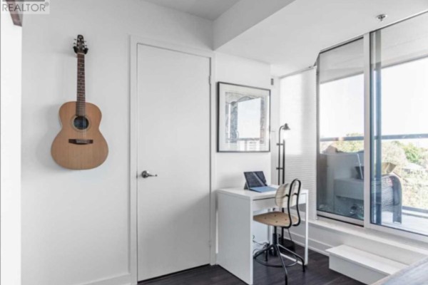 A compact workspace with a white desk, laptop, and chair next to a door and large windows. - 11 Superior Ave Avenue, Toronto