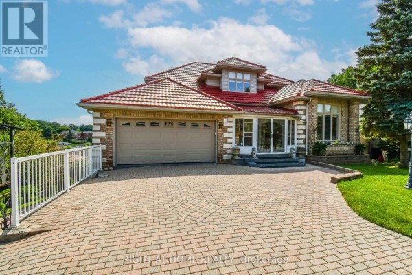 Front exterior of a brick house with a tiled roof, large garage door, and paved driveway. - 11 Thackeray Crescent, Barrie