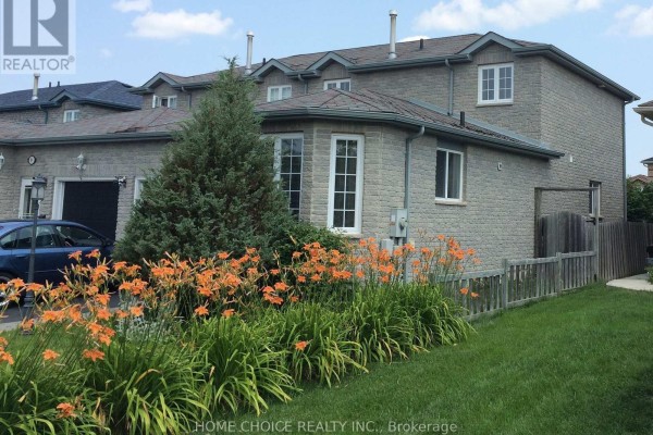 Side exterior of a beige brick townhouse with a bay window and orange flowers in the garden. - 11 Violet Street, Barrie