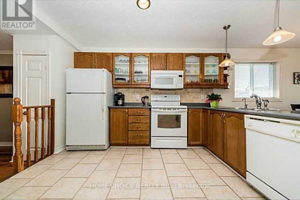 Kitchen with light tile floors, wood cabinets, white appliances, and a view of the sink and window. - 11 Violet Street, Barrie