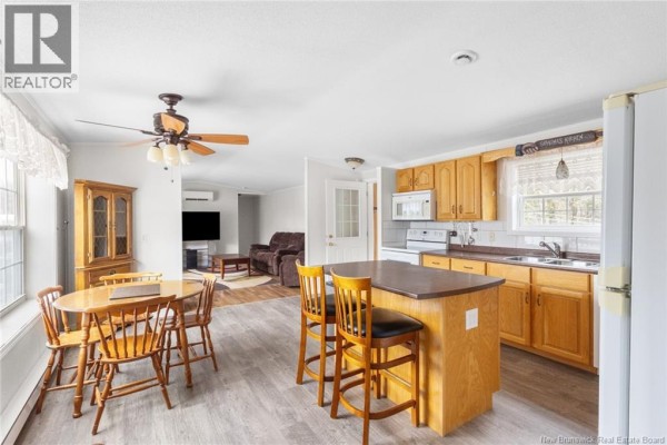 Open-concept kitchen and living area with wooden cabinets, island, dining table, and brown sofa. - 11 Wendy Crescent, Rusagonis