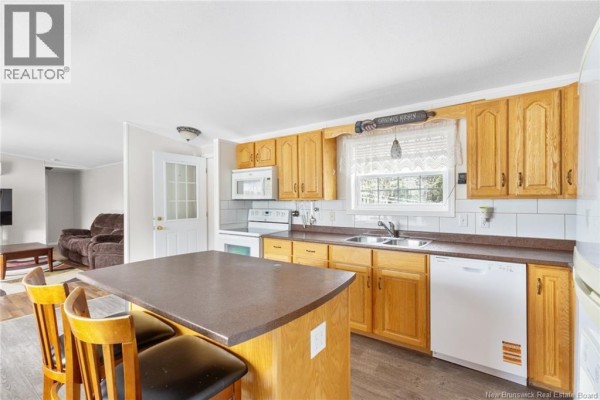 Kitchen with light wood cabinets, island with bar stools, white appliances, and a window above the sink. - 11 Wendy Crescent, Rusagonis