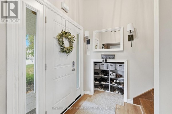 Interior front entrance hall with white door, built-in shoe storage unit, mirror, and wall sconces. - 11 William Street N, Minto