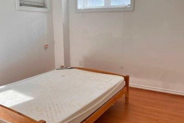 Empty bedroom with wooden bed frame and natural light from window. - 11 Zeng Cheng Drive, Markham