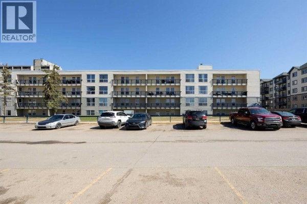 Apartment building exterior with a wide parking lot in front. - 110, 14921 Macdonald Drive, Fort Mcmurray
