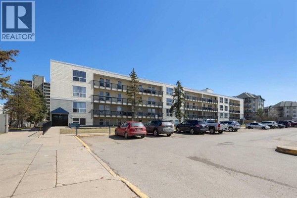 View of apartment building entrance with ramp and parking lot. - 110, 14921 Macdonald Drive, Fort Mcmurray