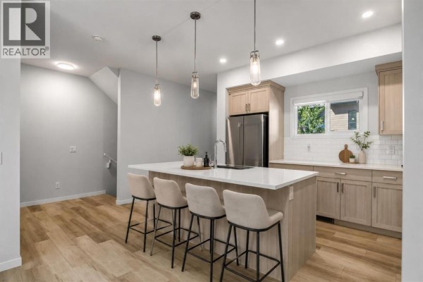 Kitchen with light wood cabinets, a large island with pendant lights, and stainless steel appliances. - 110, 42 Cranbrook Gardens Se, Calgary