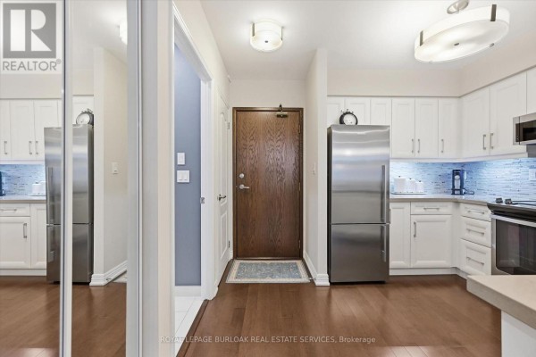 Open concept living area with kitchen island, mirrored closet doors, and bathroom. - 110 - 1276 Maple Crossing Boulevard, Burlington