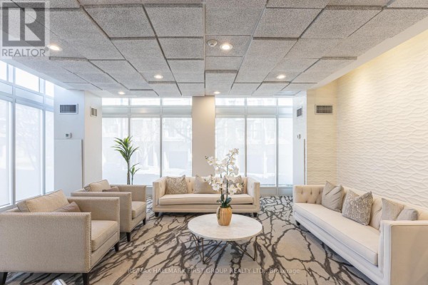 Building lobby with cream-colored sofas, armchairs, and a circular coffee table. - 110 - 25 Cumberland Lane, Ajax